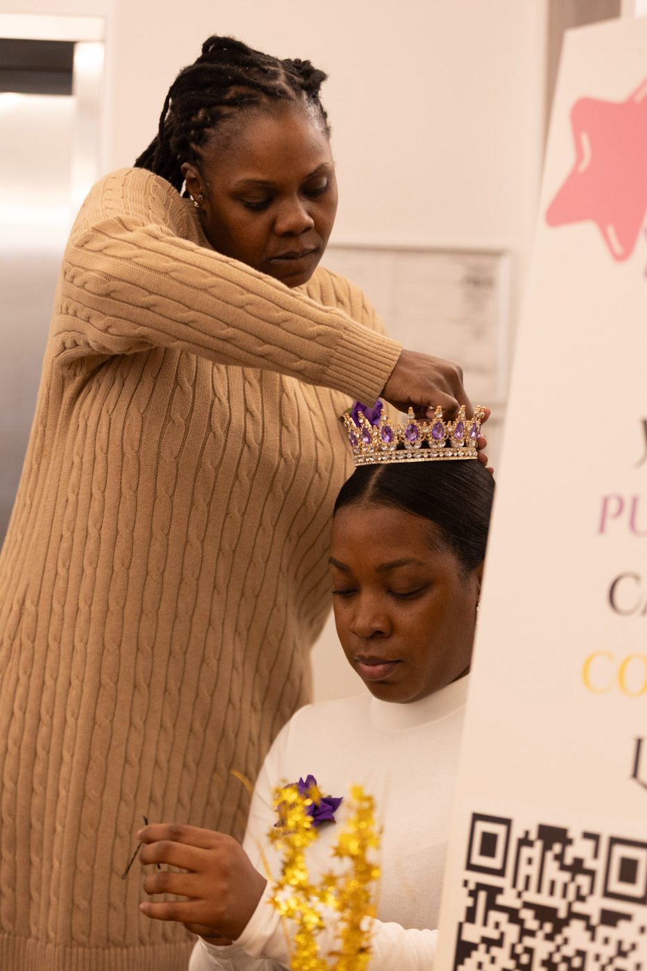 A mentor places a crown on a participant's head