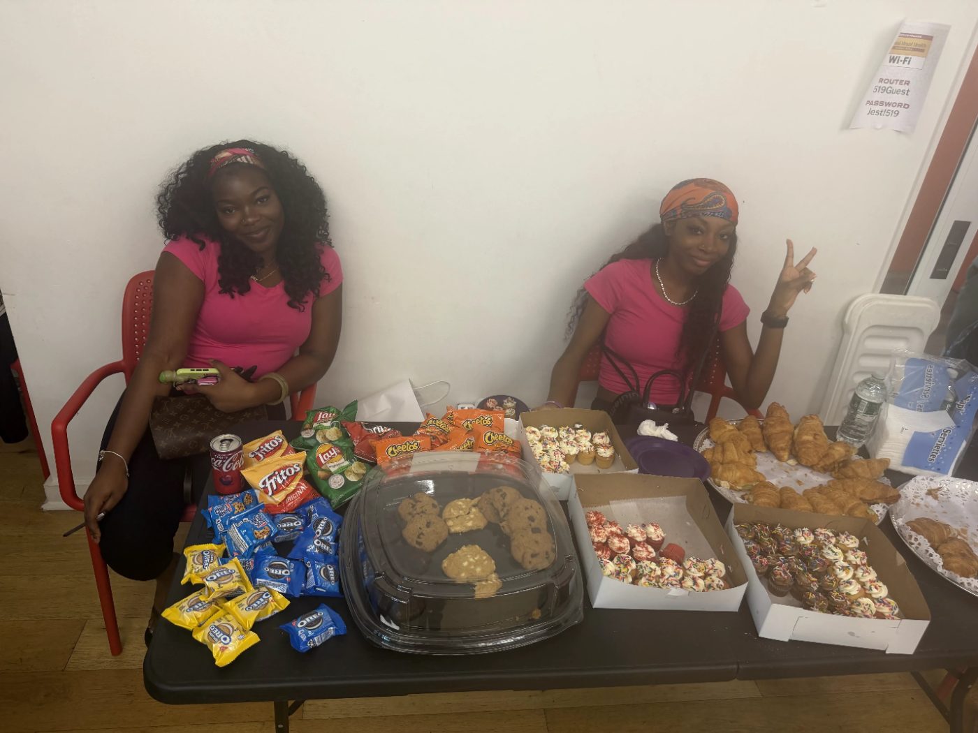 Volunteers in pink at a table of snacks